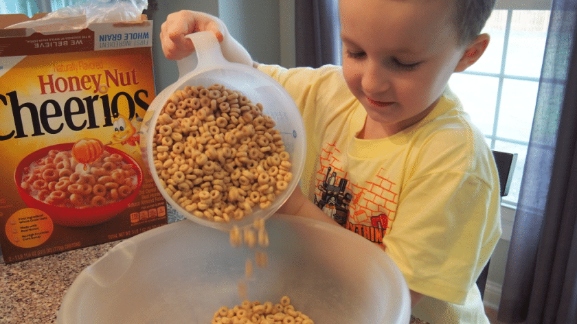 Connor pouring measured out Cheerios into bowl